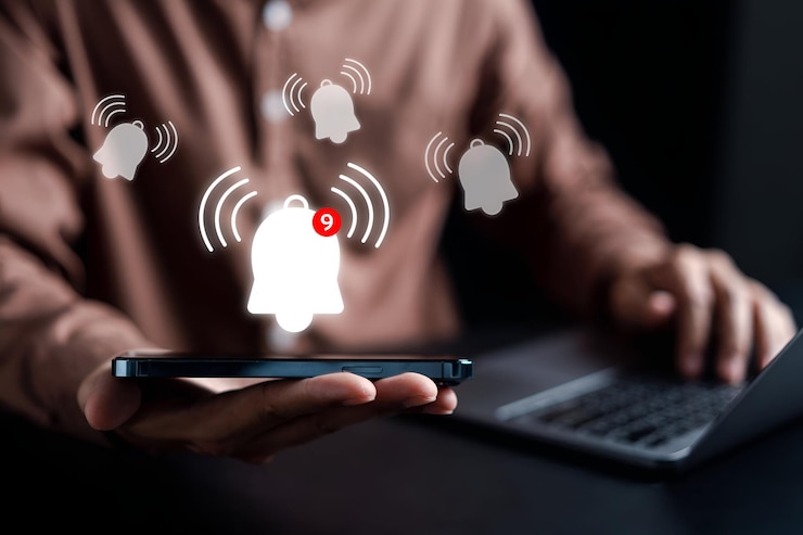 Businessman showing Notification bell button via smartphone app alerts bell ringing for application notification alert concept